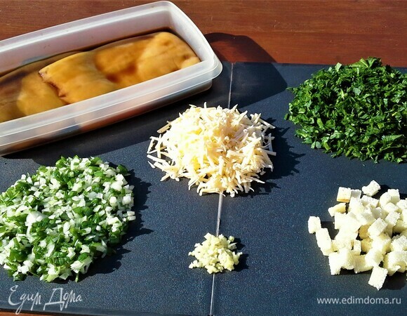 Кальмары заранее размораживаем, чистим, моем, заливаем соевым соусом и оставляем мариноваться. Белый хлеб нарезаем мелкими кубиками. Измельчаем зеленый лук вместе с белой частью, чеснок, шпинат, петрушку, укроп, кинзу — можно взять любую зелень, какая у вас есть в огороде. Сыр натереть на терке. К крошкам хлеба добавляем отварное яйцо, соль, перец, сыр, чеснок, приправу для рыбы, всю нарезанную зелень и кедровые орешки. Друзья, найдите возможность и добавьте в начинку маленькую горсточку орешков, и вы почувствуете чудесный вкус фаршированных кальмаров.