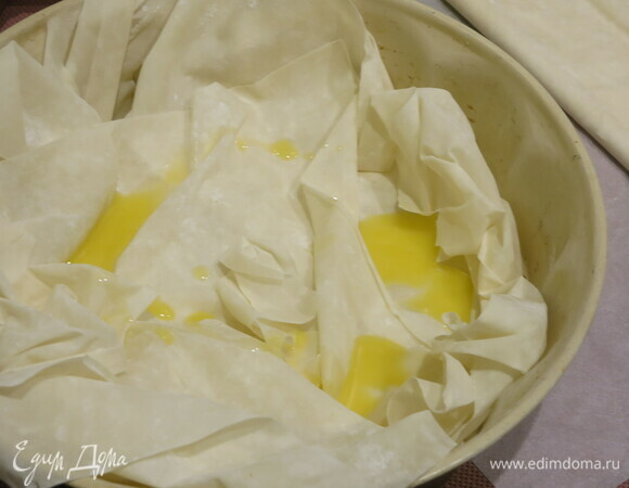 На дно формы выкладываем несколько листов теста фило и поливаем растопленным сливочным маслом.