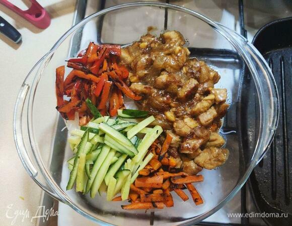 В миску с фунчозой добавить содержимое двух сковородок (мясо с луком и перец с морковью), а также нарезанные соломкой огурцы и зелень.