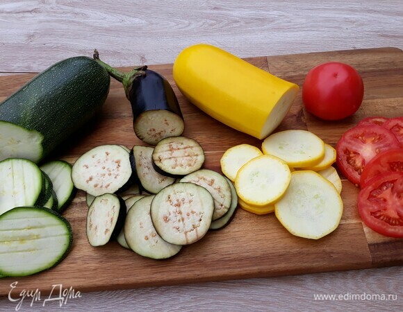 Баклажаны, помидоры, кабачки нарезать тонкими колечками. Нарезанные баклажаны посыпать солью и оставить на 20 минут, чтобы убрать горечь.