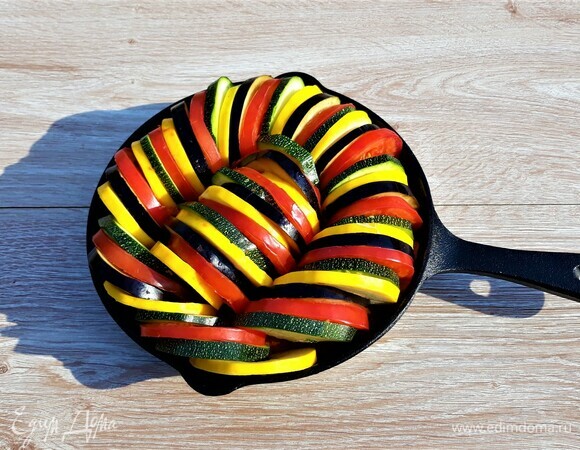 На половину соуса выложить «змейкой» колечки баклажанов, кабачков и помидоров, чередуя овощи по цвету. Оставшийся соус нанести сверху, стараясь заполнить им пространство между колечками.