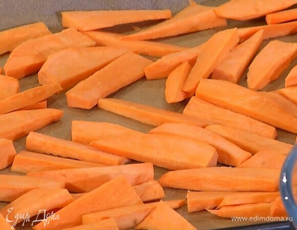 Батат почистить, нарезать небольшими брусками и выложить в один слой на противень, выстеленный бумагой для выпечки.