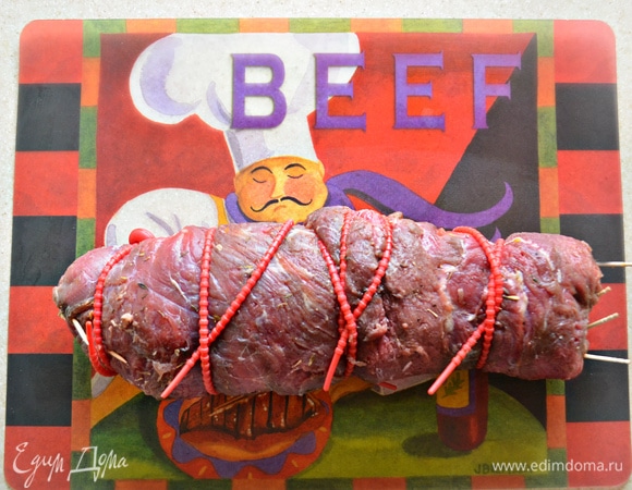 Аккуратно сверните мясо в рулет. Скрепите силиконовыми жгутами или деревянными шпажками (зубочистками). Смажьте рулет растительным маслом, поместите в форму для выпечки, накройте фольгой и поставьте в разогретую до 180°C духовку на 1 час 20 минут или 1,5 часа. 