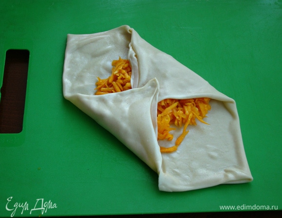 В середину сложенного квадрата равномерно выложить начинку. Сложить конвертиком, накрывая встречные углы конверта один на один.