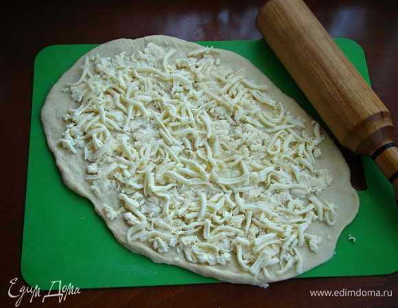 Каждую часть раскатать в овал и по всей поверхности равномерно распределить сырную начинку из адыгейского сыра и сулугуни.