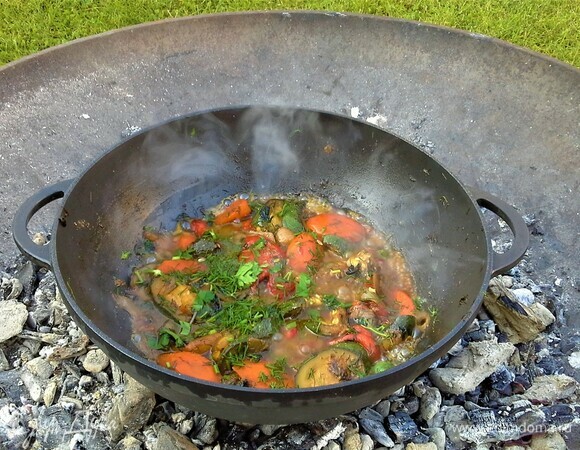 Самая вкусная еда та, что приготовлена в чугунной посуде на дровах. Зимой на даче не живем, поэтому не упускаем случая готовить вкусняшки а костре. На горячие угли поставим казан и хорошо его нагреем. Надо влить масло и обжарить лук. Добавлять овощи в такой последовательности: морковь, цукини, сладкий перец, зелень. Поэтапно все перемешивать. Добавить зелень, влить вино. Посолить, поперчить, посыпать кориандром. Перемешать, дать слегка выпариться вину. Добавить рыбный бульон. Перемешать.