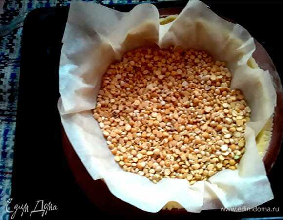 На тесто в форме укладываем бумагу и насыпаем фасоль или горох. Снова убираем в холодильник на 20 мин.