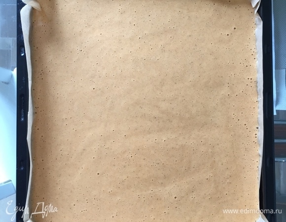 Возьмите противень размером 28х32 см, застелите поверхность бумагой для выпечки и равномерно распределите тесто. Выпекайте бисквит в разогретой до 180°C духовке 11–12 мин.