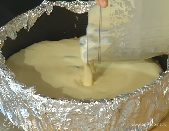 Вылить начинку на охлажденный корж, затем поставить форму в глубокий противень и влить в него горячую воду, так чтобы форма была покрыта наполовину.