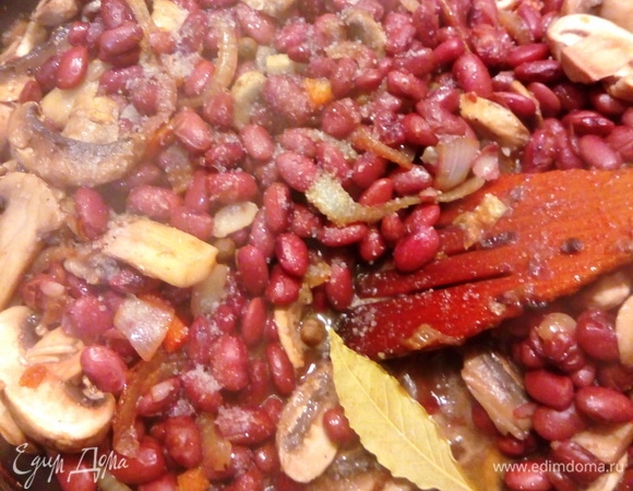 Добавляем к фасоли грибы, специи, лавровый лист и ряженку. Все перемешиваем. Тушим минут 10.