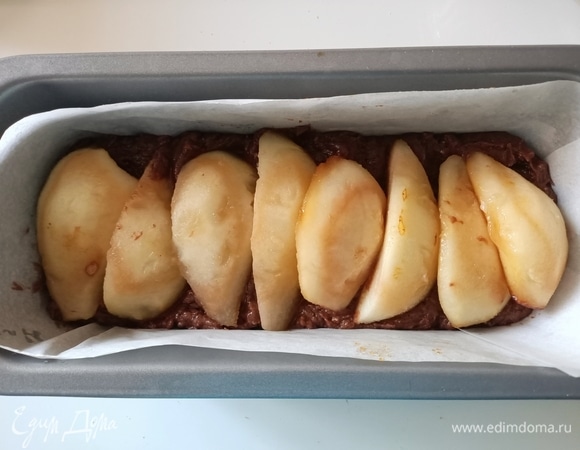 Форму для кексов застелить пергаментной бумагой или смазать маслом и посыпать мукой. Выложить половину теста. Сверху — ряд груш.