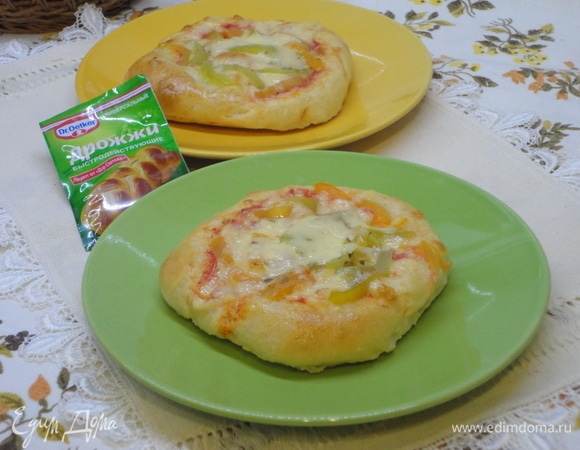 Подошедшее тесто обминаем и делим на 8–10 кусочков. Каждый раскатываем, посыпав слегка мукой. Сверху смажем томатным соусом, оставляя чистыми края на 1 см. Посыпем тертым твердым сыром. Сверху выкладываем полоски сладкого болгарского перца и посыпаем любимыми травками.