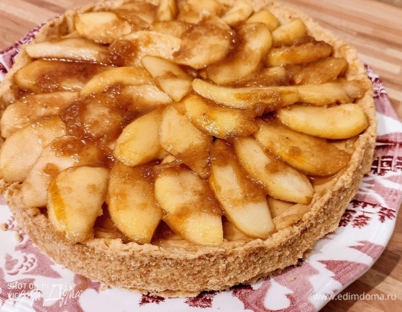 Далее очистить яблоки, разрезать их пополам, удалить сердцевину и нарезать на узкие дольки. В сковороде смешать корицу, лимонный сок, 2 столовые ложки воды и 2 столовые ложки сахара. Выложить яблочные дольки и тушить на пару под крышкой до мягкости. Учтите, что яблоки бывают разными и время их приготовления отличается. Поэтому не стоит отходить от плиты, чтобы яблочные дольки проготовились, но остались цельными. Выложить остывшие яблоки по поверхности крема. Полить яблоки соусом, оставшимся после их тушения.