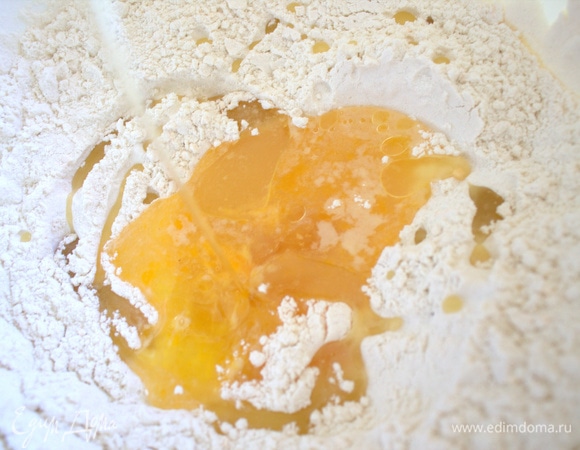 В миску просеиваем муку, делаем ямку, вливаем яйцо с водой и солью и растительное масло.