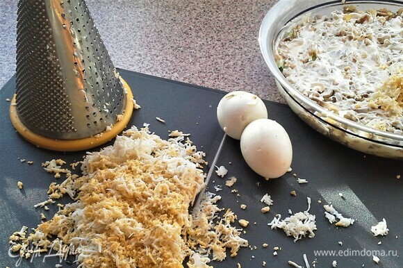Пятый слой — отварные яйца. Яйца натереть на средней терке. Посыпать на жареный лук.