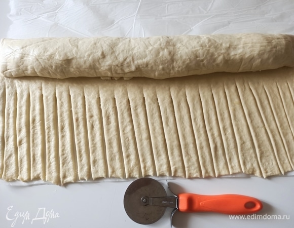 Тесто с начинкой скрутить в рулет, остальное разрезать на четное количество полосок, удобнее это делать с помощью ножа для пиццы.