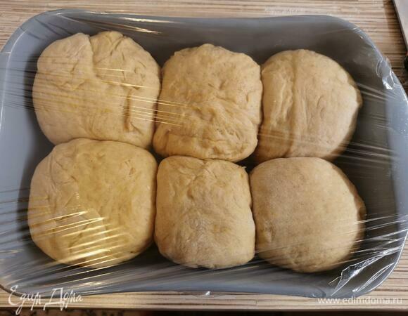 Укладываем в форму или на противень наши булочки швом вниз. Накрывам пищевой пленкой и оставляем на расстойку на 15 минут. Затем смазываем желтком и молоком и отправляем в разогретую духовку на 25 минут при 180°C.