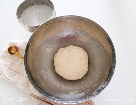 К муке добавляем соль, сахар, молоко и замешиваем тесто. Края емкости смазываем растительным маслом, кладем туда тесто и накрываем полотенцем. Оставляем тесто подниматься на 1,5 часа.