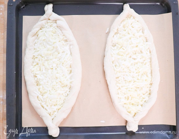 Выкладываем начинку на тесто, разравниваем ее до краев. Аккуратно начинаем сворачивать края и защипываем на концах. Отправляем хачапури выпекаться в духовку на 15 минут при 200°C. Достаем наши лодочки, аккуратно выкладываем желток и снова ставим в духовку на 2 минуты. Наши хачапури готовы! Приятного аппетита!