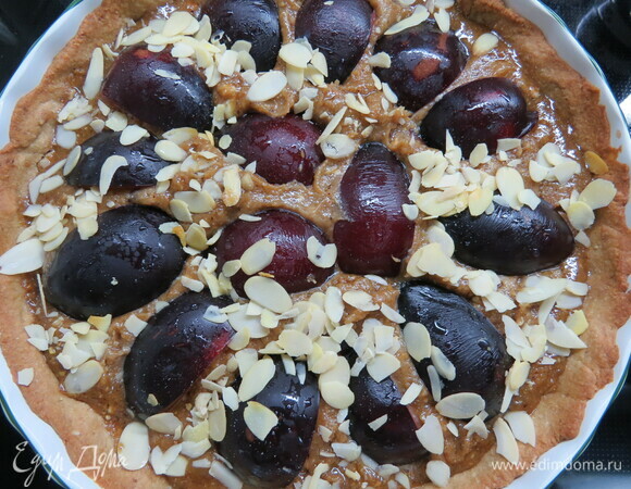 Выложить на тарт миндальный крем, разровнять, сверху (не вдавливая) разложить сливы, украсить миндальными лепестками. Выпекать 30 минут.