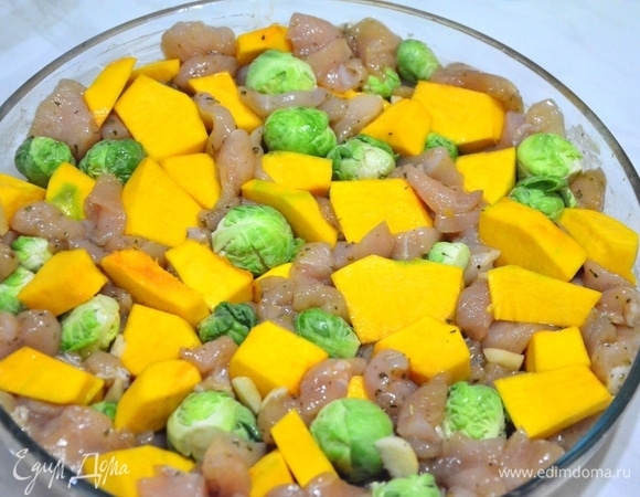 Замаринованное филе выкладываем ровным слоем на смазанную растительным маслом форму для запекания. Тыкву и капусту равномерно распределяем по курице, немного вдавливая их между кусочками филе.