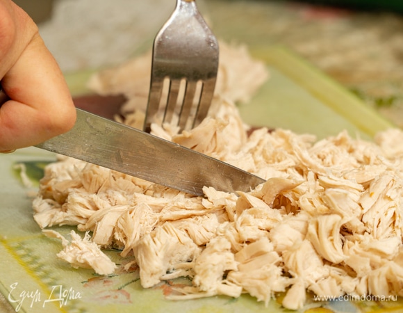 Вареную курицу вытащить из кастрюли, поместить на разделочную доску, нарезать небольшими кусочками, затем снова вернуть в суп.