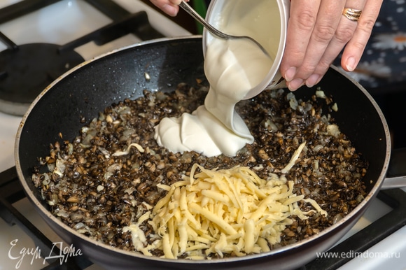 Добавить в сковороду 50 г тертого сыра и сметану, перемешать ингредиенты. Снять готовую грибную начинку с огня после расплавления сыра.