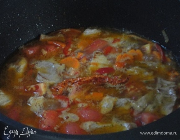 Затем — нарезанные кусочками помидоры и измельченный чеснок. Острый перец целиком положить на картофель. Перемешать, вылить бульон и тушить при медленном кипении 20 минут.