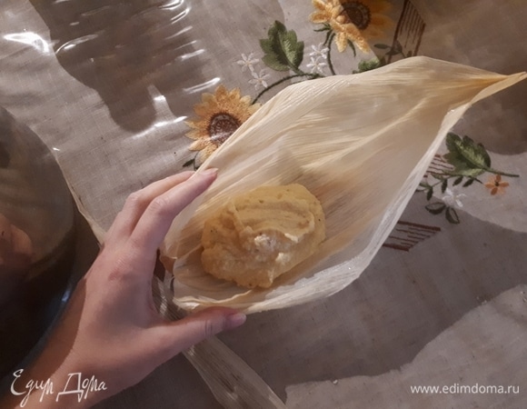 Возьмите лист кукурузы и оторвите тонкую полоску сбоку. Выложите 1–2 ст. л. теста на четверть листа ближе к основанию, но не впритык.