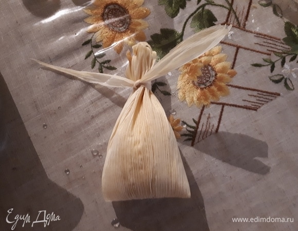 Затем сложите лист пополам и завяжите сверху оторванной полоской листа. Не бойтесь затягивать — кукурузные листья довольно прочные.