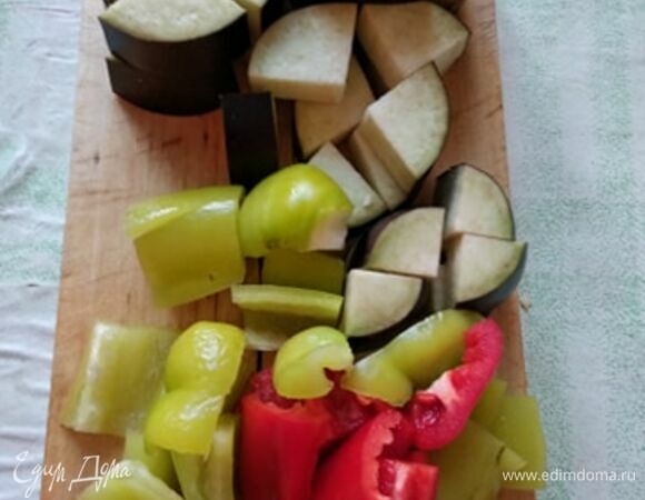 Крупно нарезать баклажан и перец. Лук — полукольцами. Все овощи сложить в казан к курице или в кастрюлю с толстым дном. Добавить зиру и кориандр. Семена перетереть ладонями, кусочки должны чувствоваться. Добавить горячей воды, довести до кипения и тушить на медленном огне.