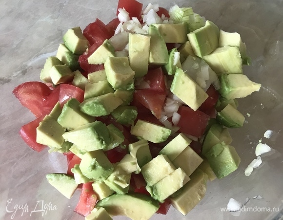 Авокадо и помидор нарезать крупными кубиками. Лук и чеснок мелко нашинковать. Переложить все в миску, сбрызнуть лимонным соком и аккуратно перемешать.