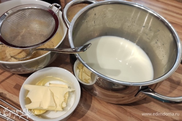 Горячее молоко процедить через мелкое сито и сразу тонкой струйкой влить в смесь яичных желтков, тщательно размешать.