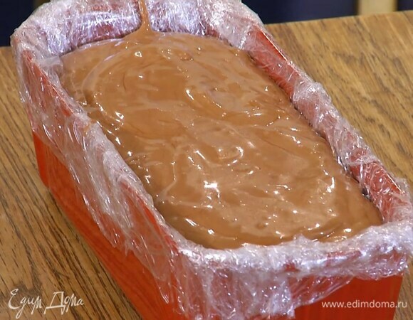 Форму для выпечки выстелить пищевой пленкой, влить шоколадную массу, затянуть сверху пленкой и отправить в морозильник на 5–6 часов.