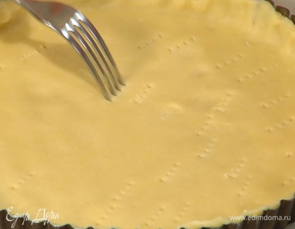 Дно формы застелить бумагой для выпечки, выложить тесто так, чтобы получились ровные бортики, и часто наколоть его вилкой, затем накрыть бумагой для выпечки, засыпать любыми бобовыми и выпекать в разогретой духовке 15–20 минут.