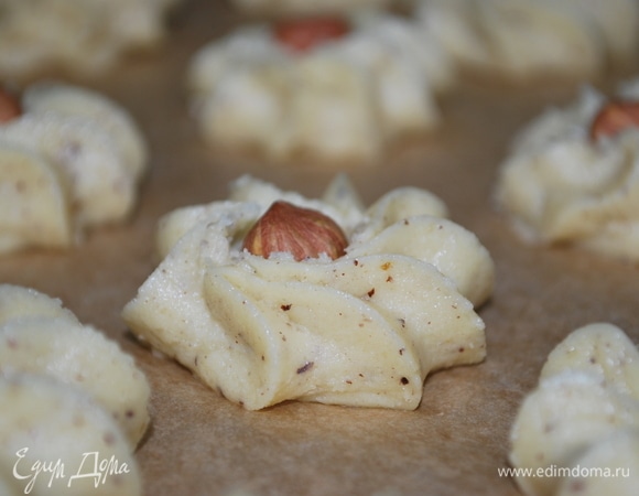 Выдавить порционно печенье из кондитерского мешка, в середину печенья выложить по ореху и выпекать при 170°C примерно 15 минут.