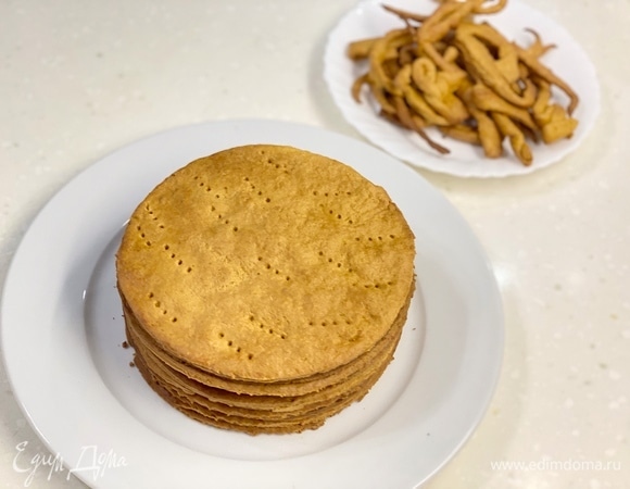 Остывшие коржи собрать в стопку, а обрезки измельчить любым удобным способом в крошку.