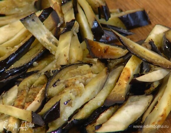 Противень выстелить фольгой, выложить в один слой кружки баклажана, слегка посолить, поперчить, сбрызнуть оливковым маслом Extra Virgin и отправить под разогретый гриль на 7–10 минут, затем нарезать полосками.