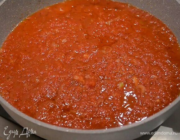 Приготовить томатный соус: разогреть в сковороде оливковое масло, выложить лук с чесноком, добавить перец чили и обжарить, добавить измельченные томаты в собственном соку и прогреть все на маленьком огне.