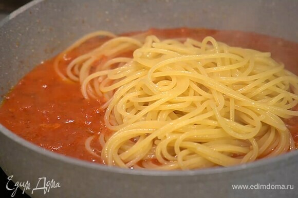 Отваренные спагетти переложить в сковороду с томатным соусом, посолить, перемешать и переложить в блюдо.