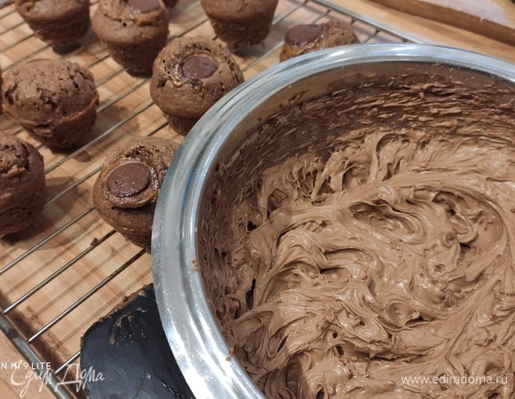 Пока капкейки остывают, взбить крем. Для этого соединить в миске размягченное сливочное масло с сахарной пудрой и вашей любимой шоколадной пастой, взбить до кремовой консистенции. Крем выложить в кондитерский мешок.