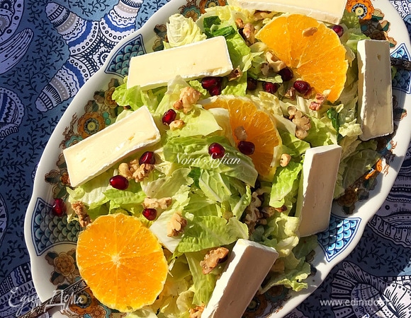 Переложить салат на блюдо, посыпать орехами, гранатом и украсить апельсином и сыром.