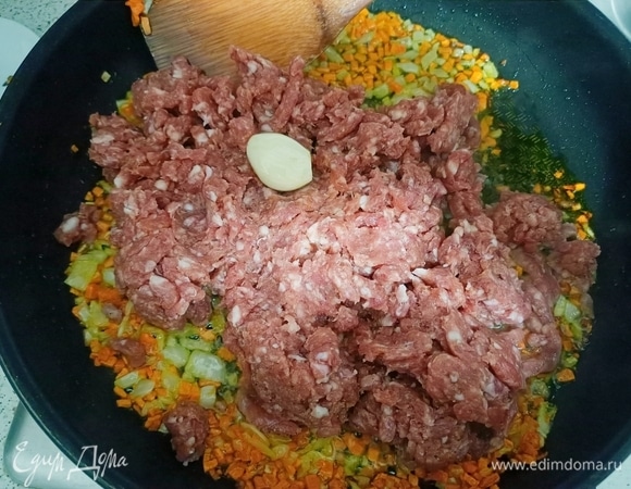 Добавить зубчик чеснока и мясной фарш, предварительно посолив и приправив его приправами. Обжарить в течение нескольких минут. Затем влить вино.