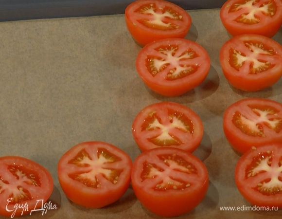 Помидоры разрезать пополам и выложить на противень, застеленный бумагой для выпекания.
