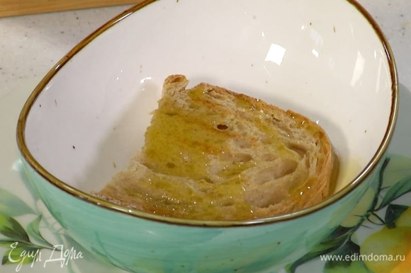 Приготовить гренки: хлеб обжаривать с двух сторон на сухой сковороде-гриль до появления румяных полосок, затем почистить оставшийся чеснок, слегка смазать им хлеб, выложить его в суповые тарелки и сбрызнуть оставшимся оливковым маслом.