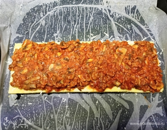 Мясное рагу разделить на три части. Лист поленты посыпать тертым сыром и выложить соус, сверху накрыть вторым листом поленты, посыпать тертым сыром и выложить часть начинки.