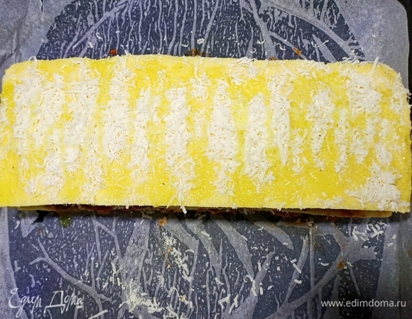 Затем начинку накрыть третьим слоем поленты, посыпать сыром, полить оливковым маслом и отправить противень с полентой запекаться в духовку при температуре 190°C на 15–20 минут.