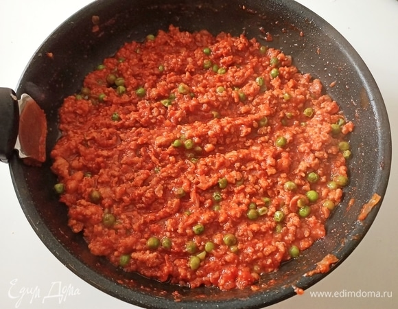 В сковороду добавить два вида масла, мелко нарезанный лук и мясной фарш. Немного обжарить на сильном огне, затем огонь уменьшить, влить вино и тушить. Когда жидкость испарится, влить томатную пасту и добавить зеленый горошек. Посолить, поперчить и тушить. Должно получиться достаточно густое мясное рагу.