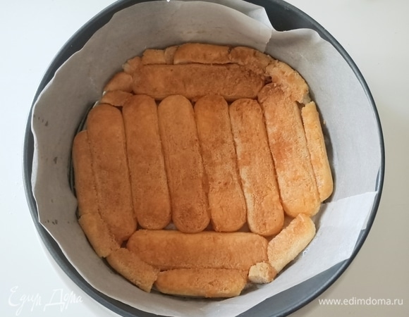 На круглое блюдо поставить кольцо от разъемной формы (22–24 см). На дно уложить печенье, предварительно окунув его в яблочный или любой другой фруктовый сок.