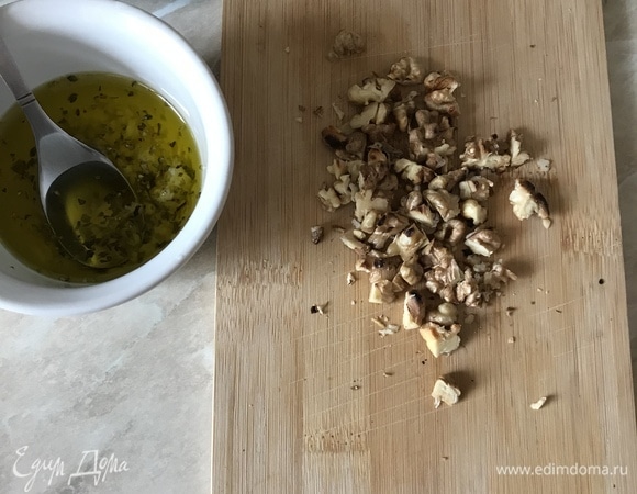 Пока жарятся сухарики, приготовим заправку. В пиале смешать оливковое масло, чеснок (лучше выдавить через пресс), орегано и хорошо перемешать. Орехи прокалить на сковороде, очистить от шелухи и порубить ножом.